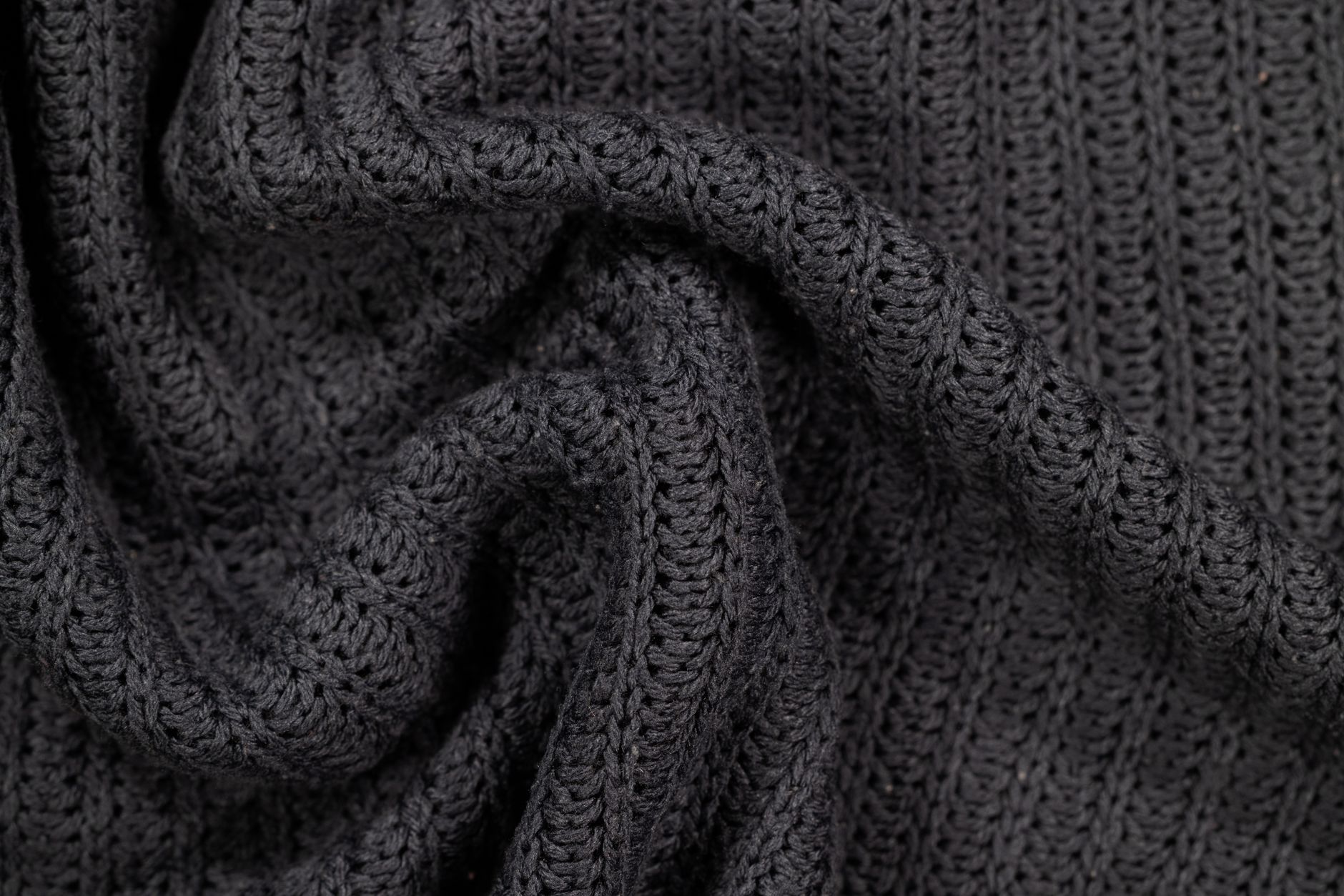 Detailed macro shot of gray knitted fabric showcasing intricate crochet texture.