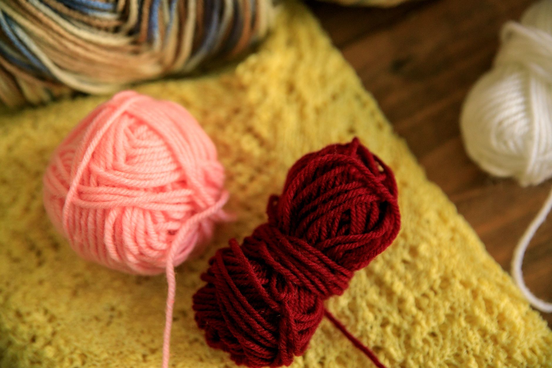 Close-up of vibrant yarn balls on a yellow knitted fabric, perfect for crafting.