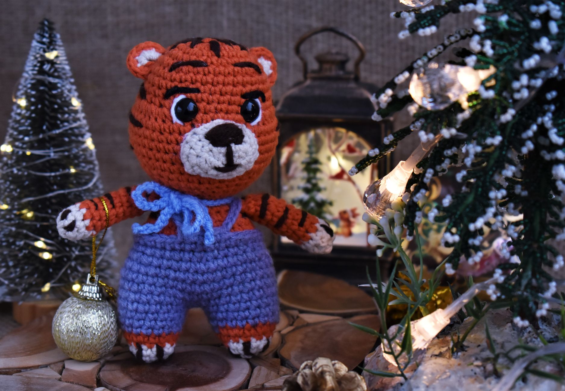 Adorable crocheted tiger plush toy amidst festive Christmas decorations, creating a cozy holiday atmosphere.