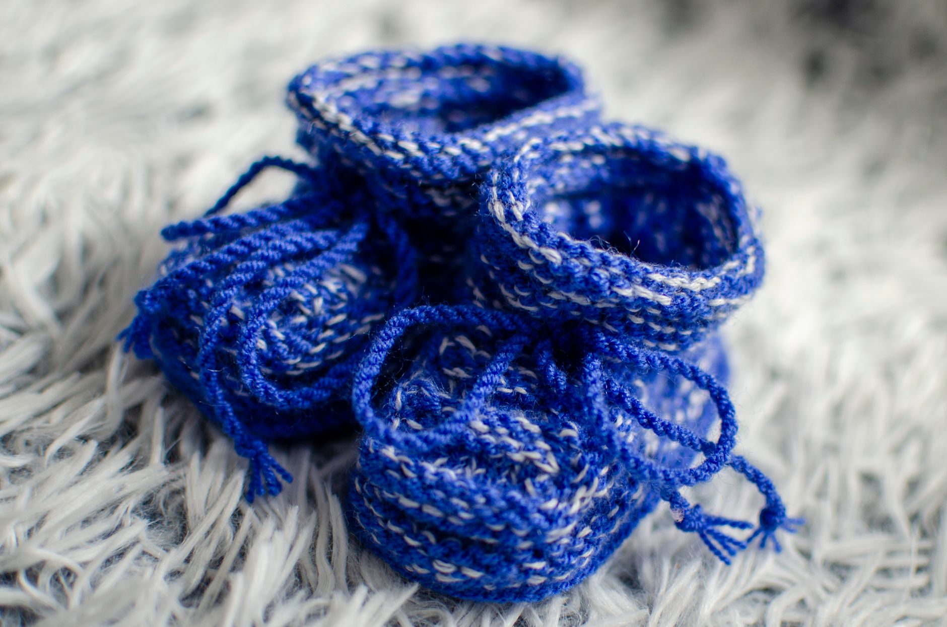 Close-up of knitted blue baby booties on soft textile, ideal for baby care themes.