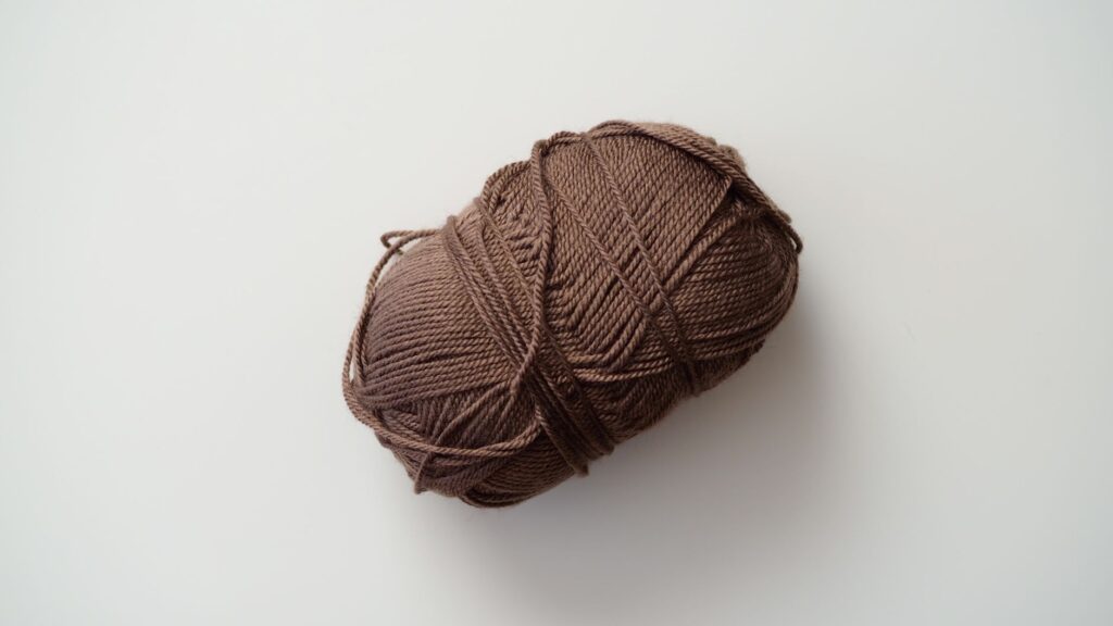 Close-up of a brown yarn ball on a simple white background, ideal for knitting and crafts imagery.