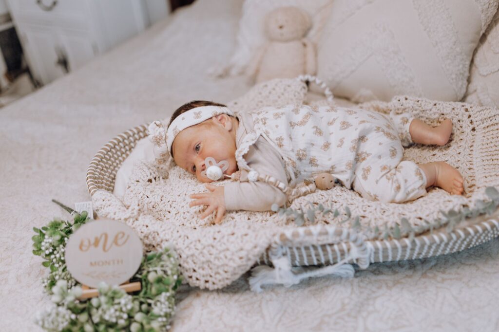 Charming one-month-old baby resting with pacifier on cozy bed, symbolizing early childhood serenity.