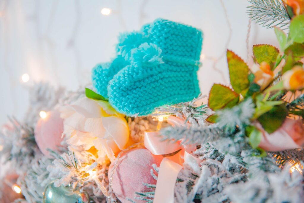 Blue baby booties nestled in festive Christmas decor, creating a warm holiday ambiance.