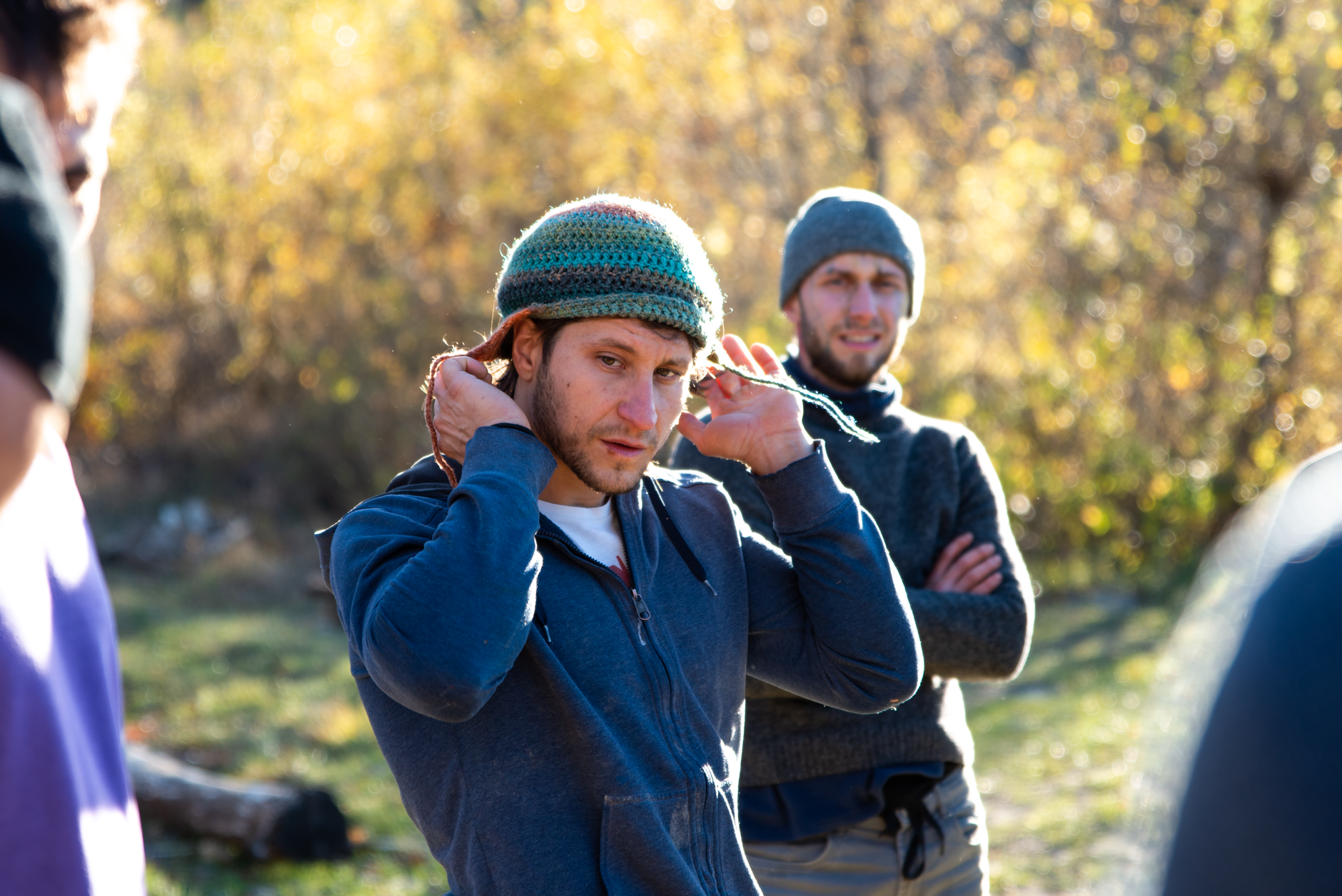 Casual outdoor meeting of adults in a sunny fall setting, wearing warm clothing.