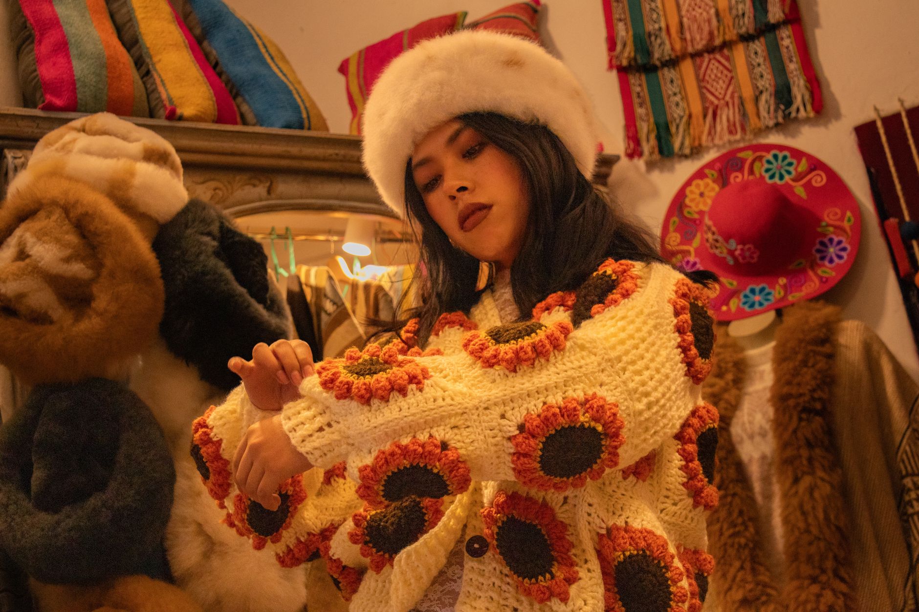 Woman in a cozy crocheted sweater and fur hat exploring a vintage fashion store.