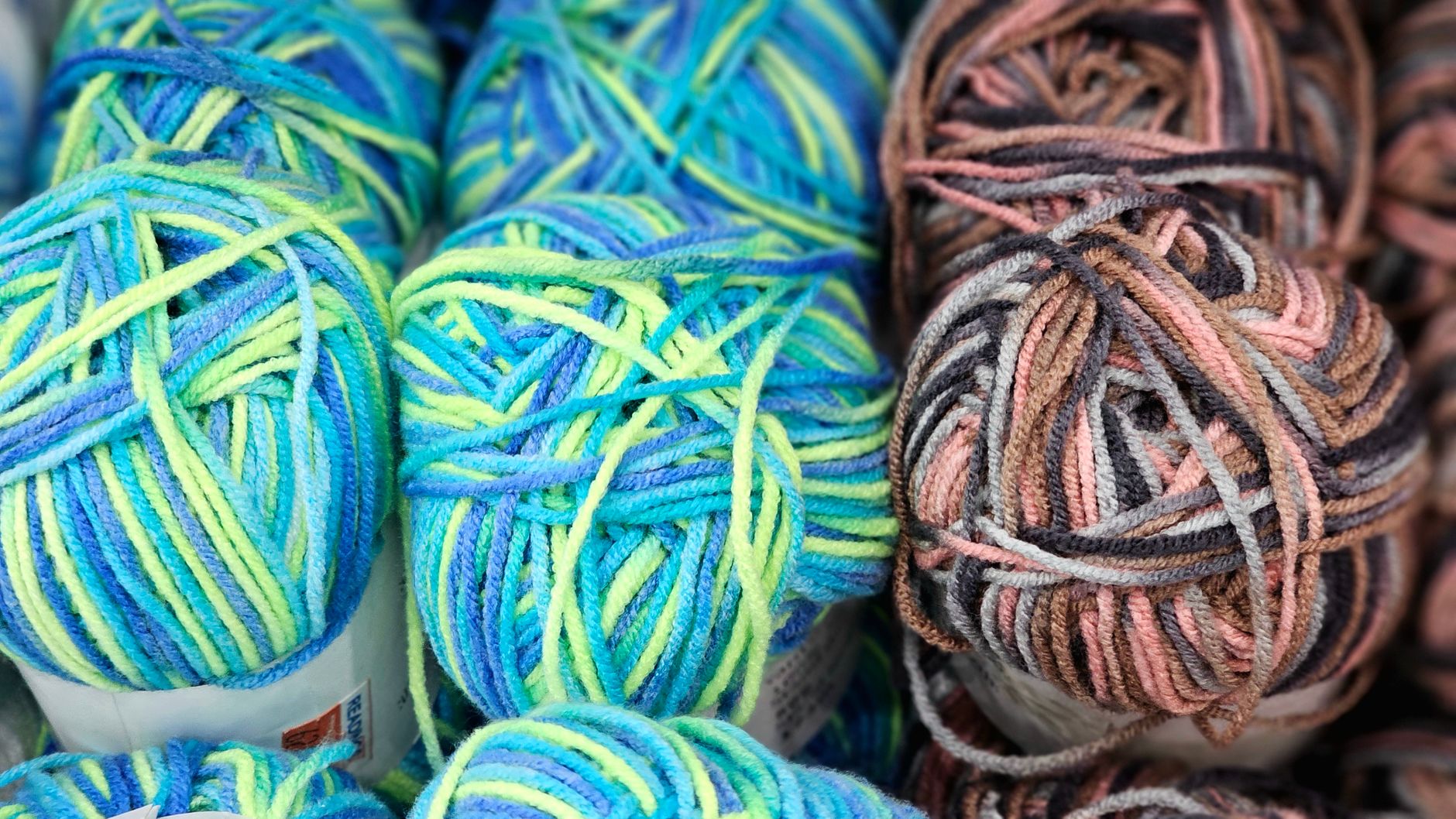 Close-up of colorful yarn balls in blue, green, and brown hues, ideal for knitting projects.