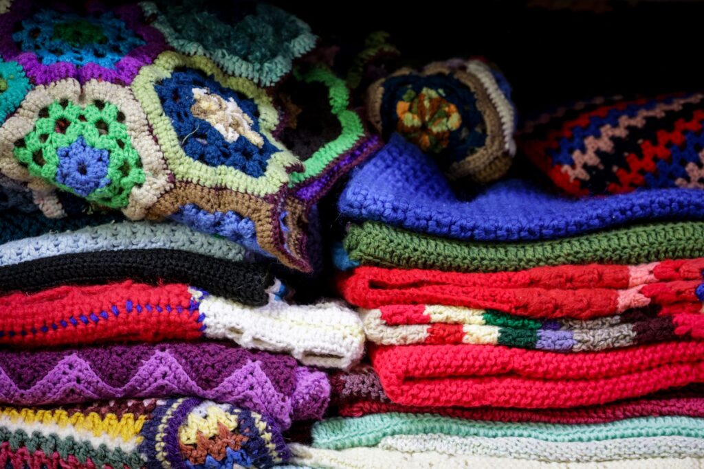 A vibrant stack of vintage crochet blankets showcasing intricate patterns and colorful designs.