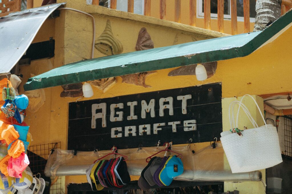 Outdoor market stand displaying colorful hats and crafts under a green awning.