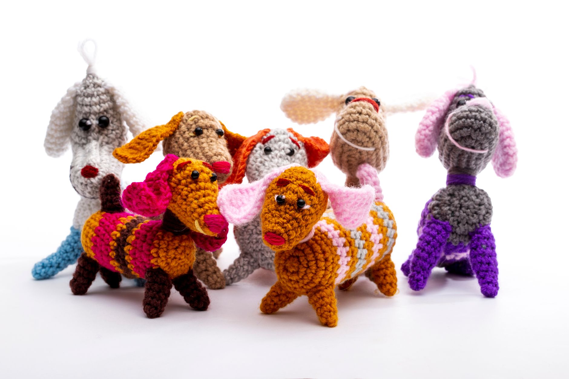 Vibrant handcrafted crochet dog toys displayed on a white background.