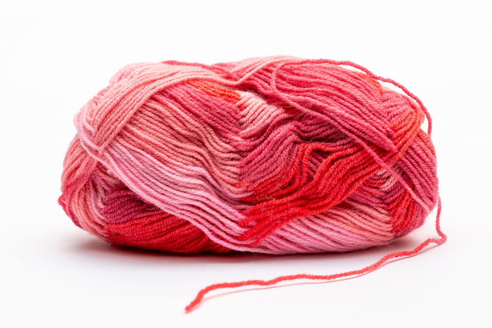 A skein of vibrant pink and red yarn against a clean white backdrop, perfect for knitting and crochet projects.
