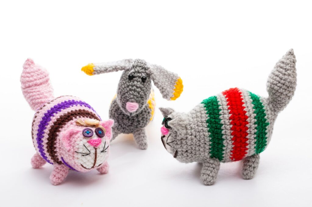Brightly colored handmade crochet animal toys against a white background, showcasing creativity and craftsmanship.