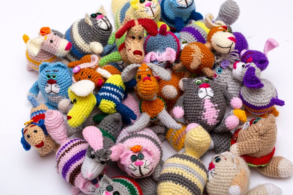 Vibrant assortment of handmade knit stuffed animal toys arranged together, showcasing intricate designs and bright colors.