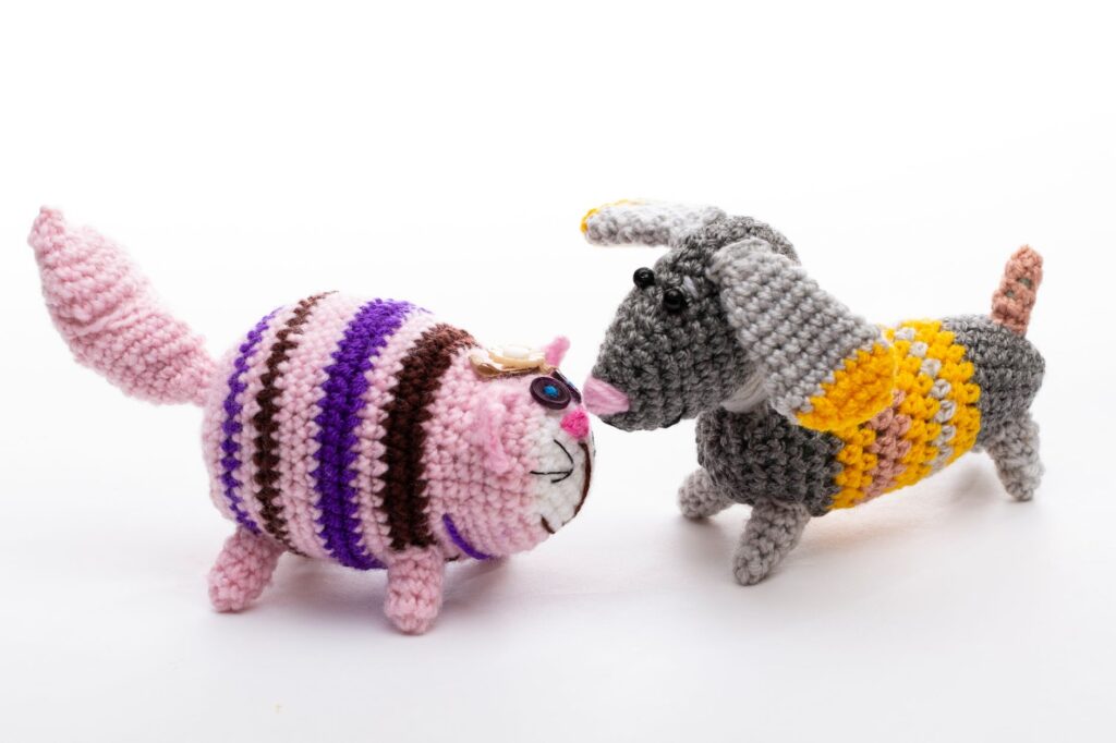 Colorful crochet cat and dog handmade toys displayed against a plain white backdrop.