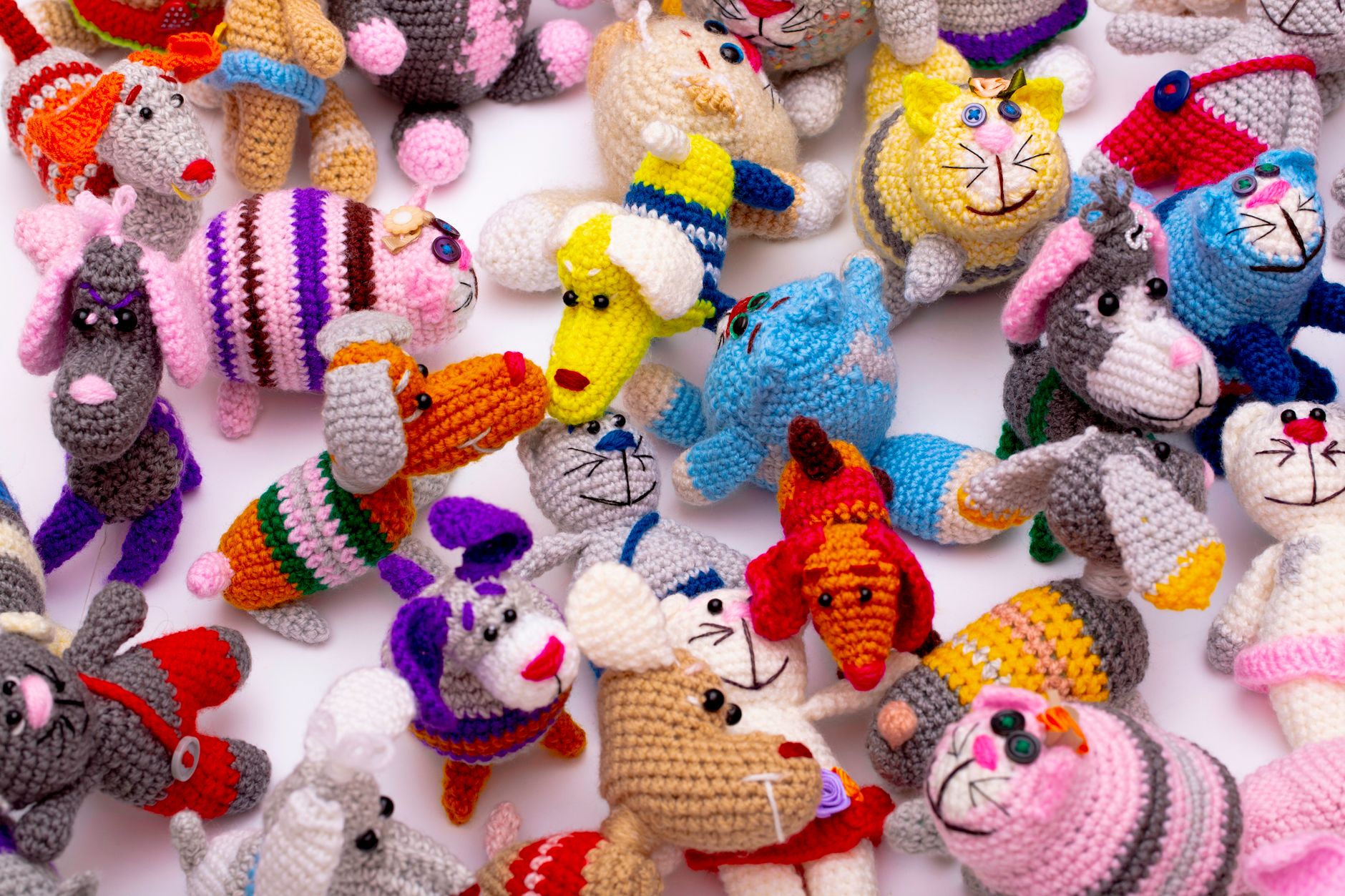 Vibrant collection of hand-knitted animal toys in playful colors and designs.