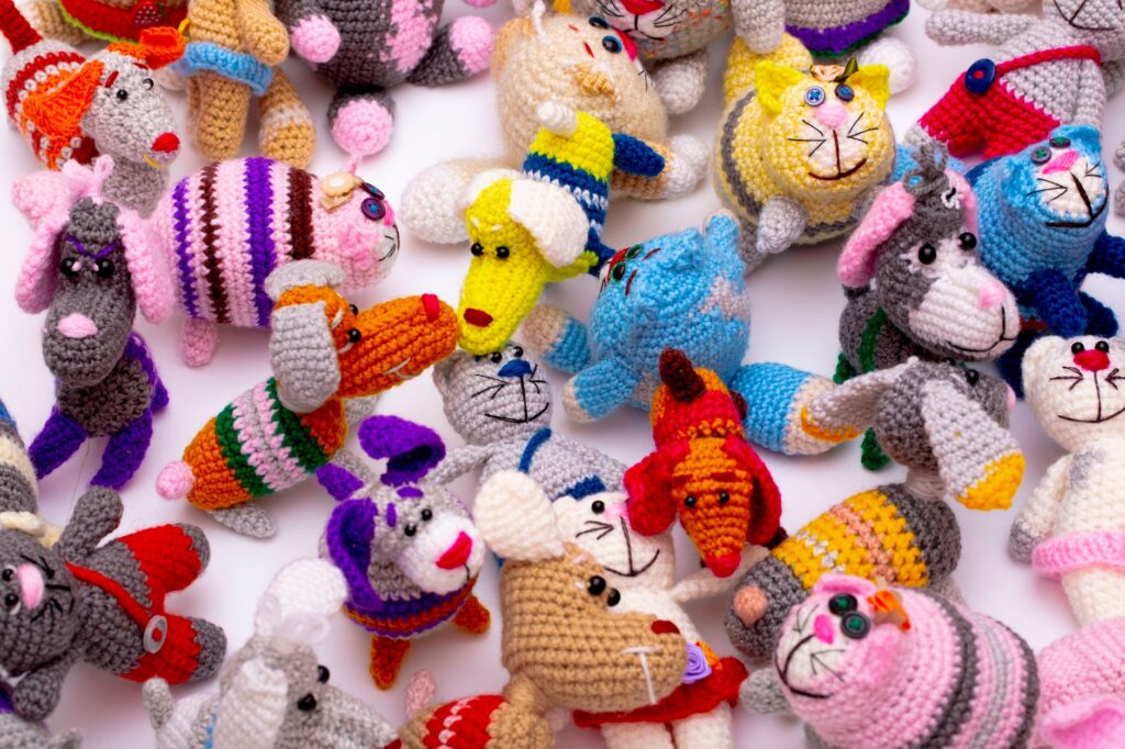 Vibrant collection of hand-knitted animal toys in playful colors and designs.