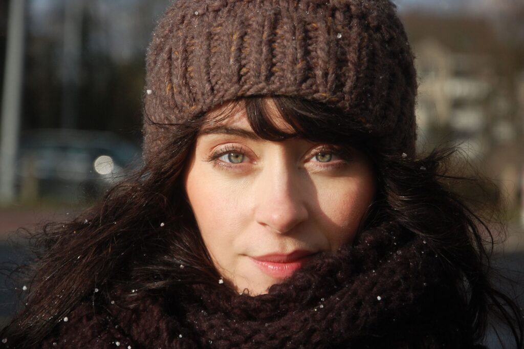Close-up of a woman in winter attire with falling snowflakes.