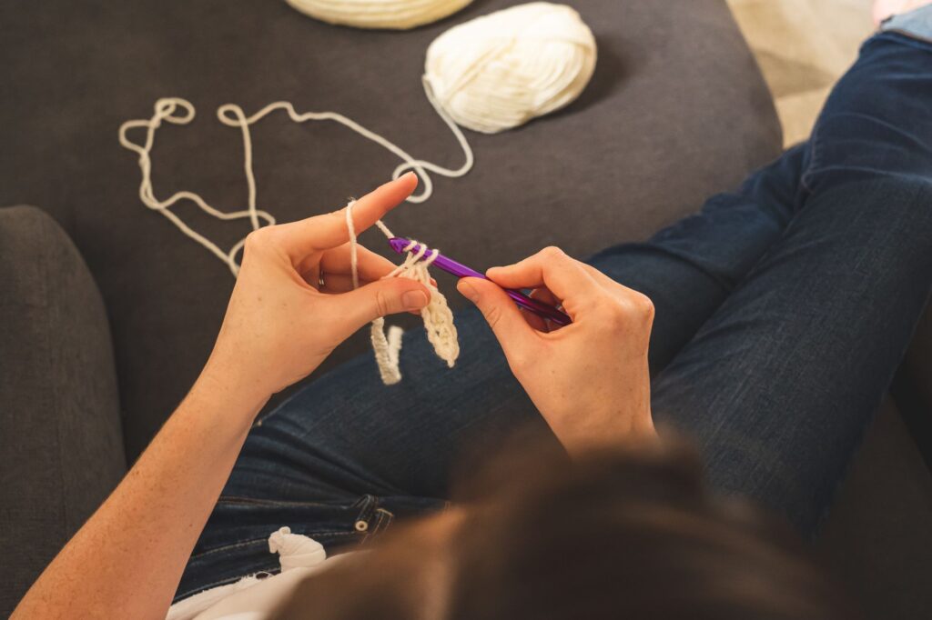 A person enjoys a relaxing hobby of crocheting with yarn indoors, creating handmade crafts.
