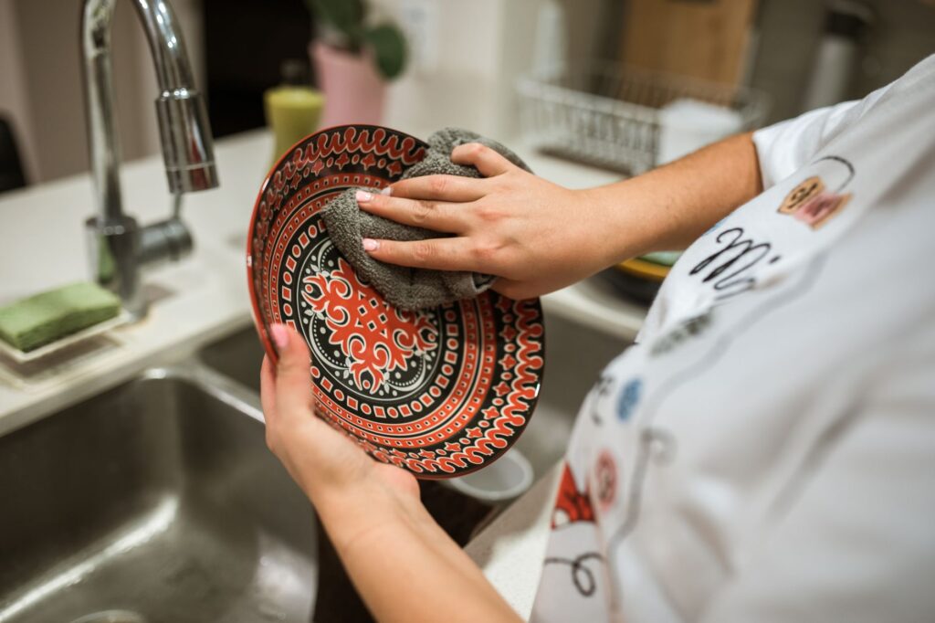 Close-up of hands washing a vibrant patterned plate at home in a modern kitchen.