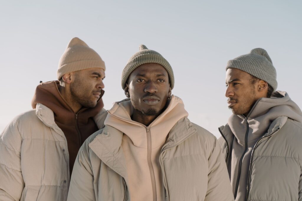 Three men in stylish winter attire showcasing modern fashion trends outdoors.