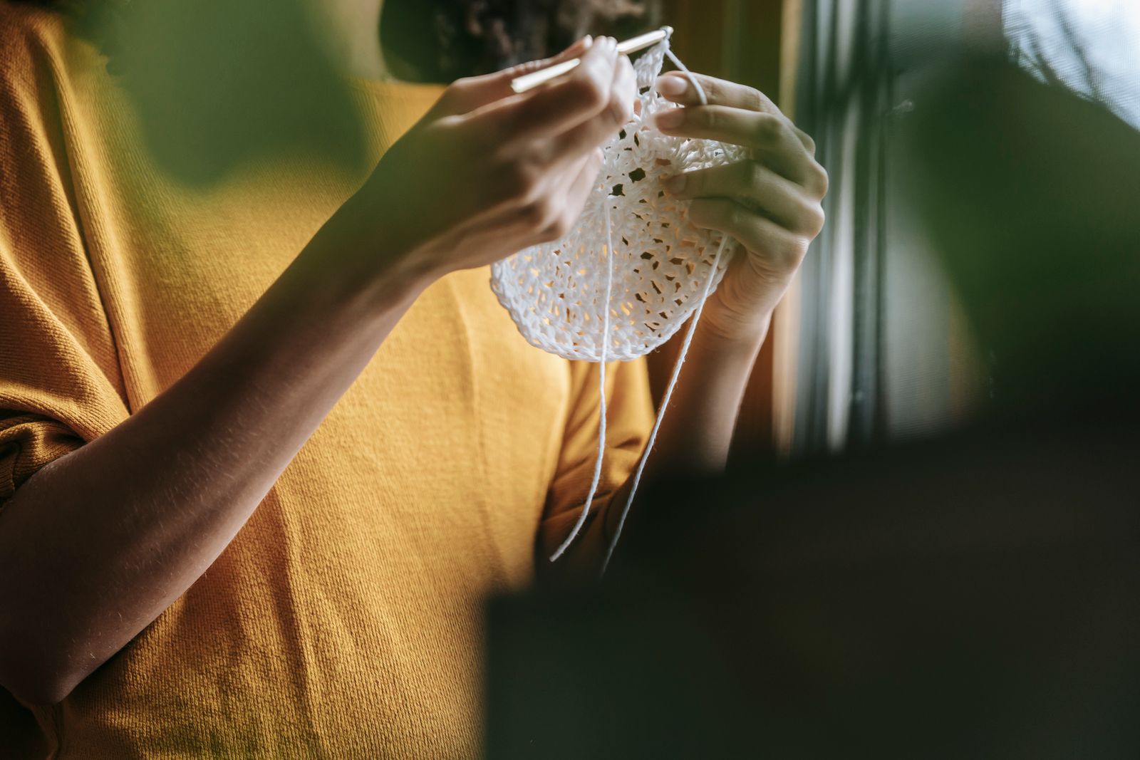 Close-up of a person crocheting indoors, emphasizing leisure and craftsmanship.