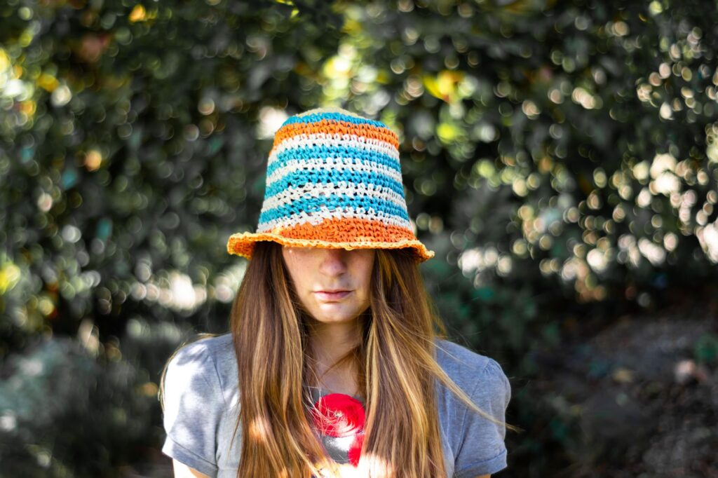 A woman wearing a colorful knitted cap and gray shirt outdoors.